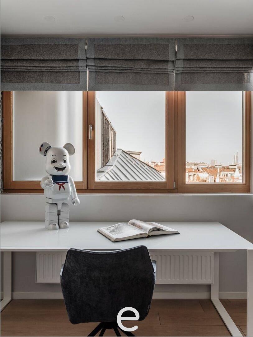 Heller Arbeitsbereich mit Schreibtisch, Stuhl und Blick auf die Dächer der Stadt, ideal für konzentriertes Arbeiten.
