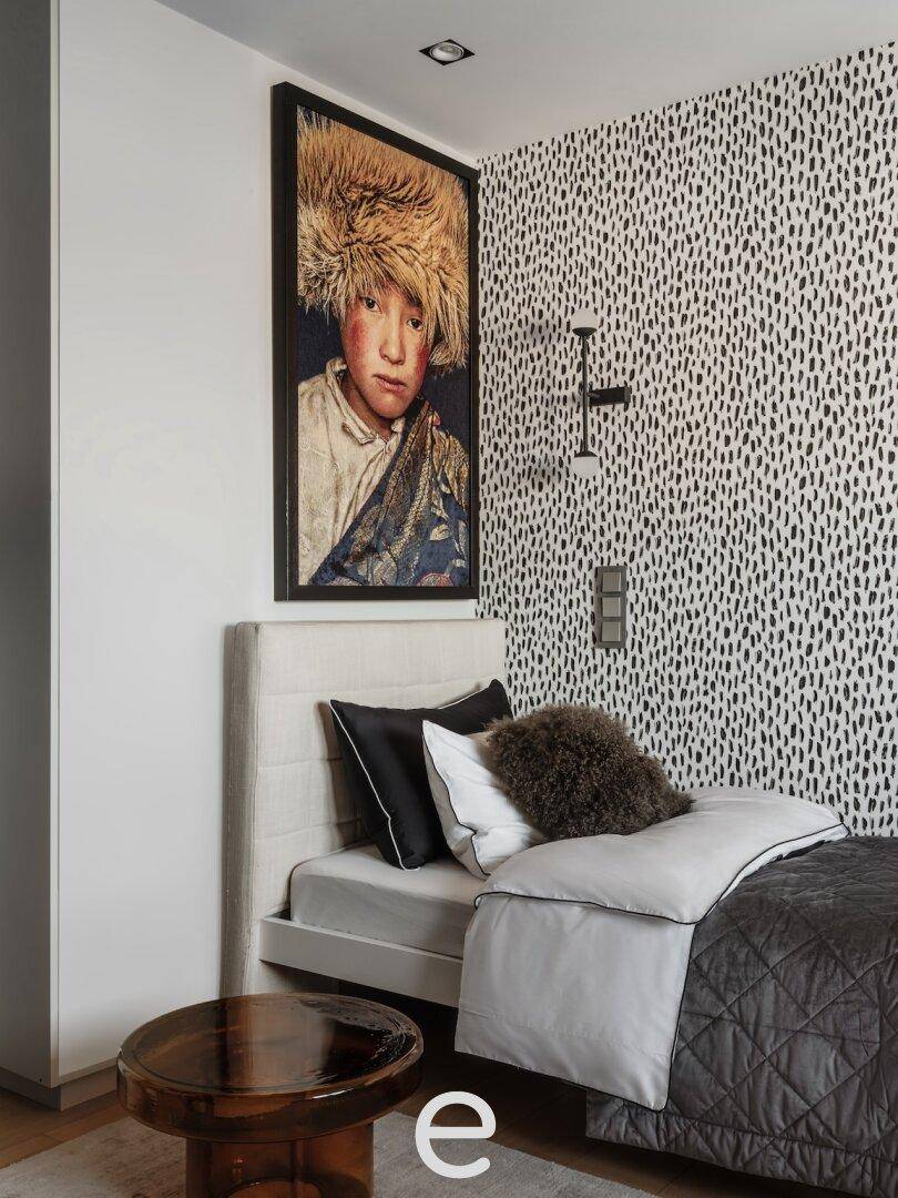 Modernes Schlafzimmer mit Einzelbett, gemusterter Tapete und Kunstwerk, das eine persönliche Note verleiht.