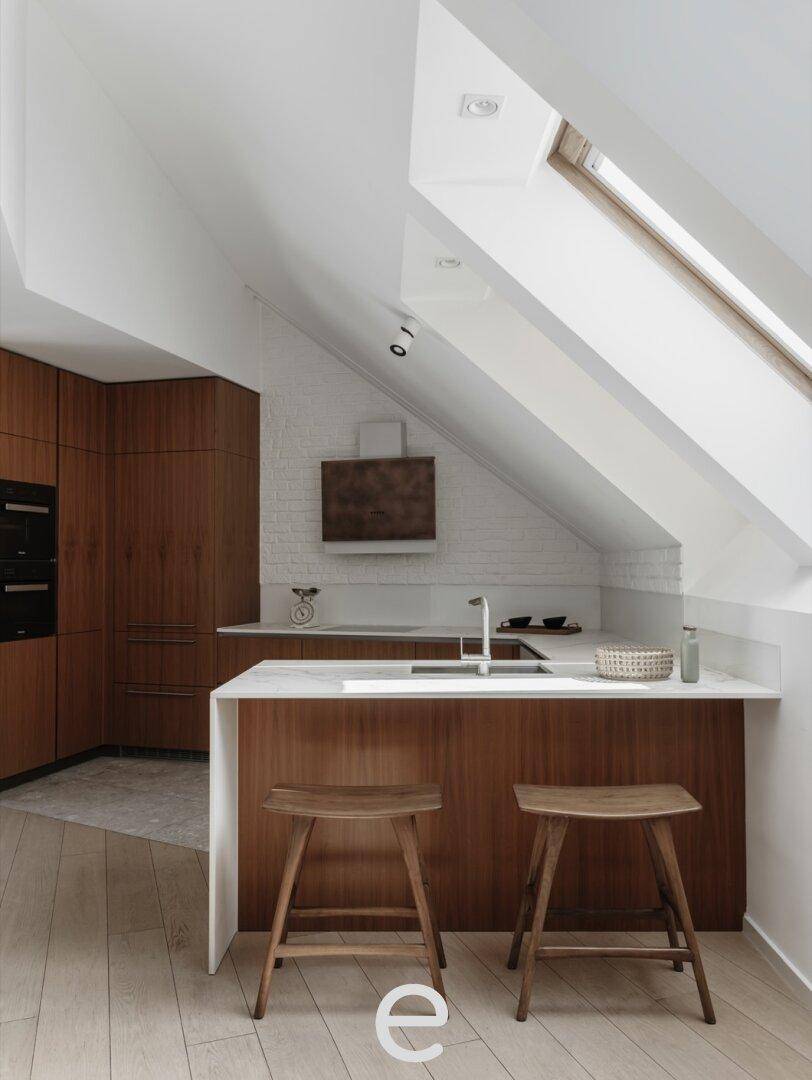 Moderne Küche mit Holzfronten, weißer Arbeitsplatte und Dachfenstern für viel Licht und Atmosphäre.