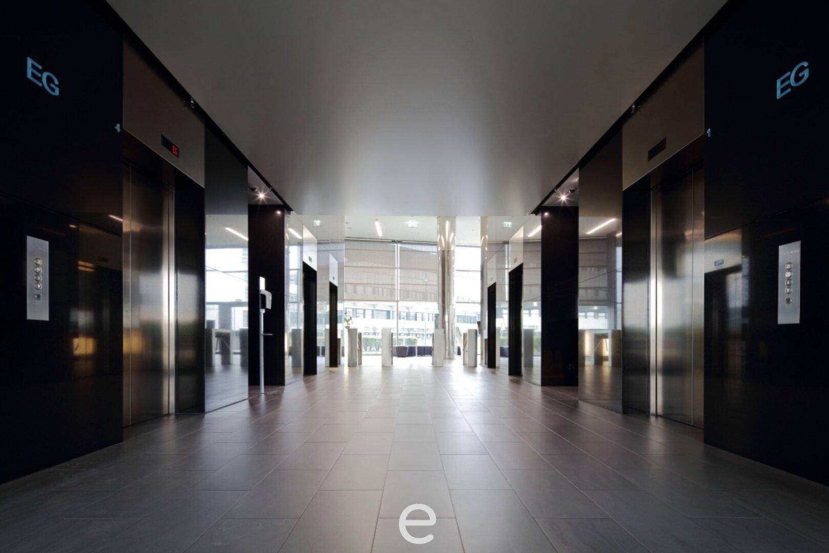 Dunkle, moderne Lobby mit glänzenden Aufzügen und Fliesenboden, die einen luxuriösen Eindruck vermittelt.