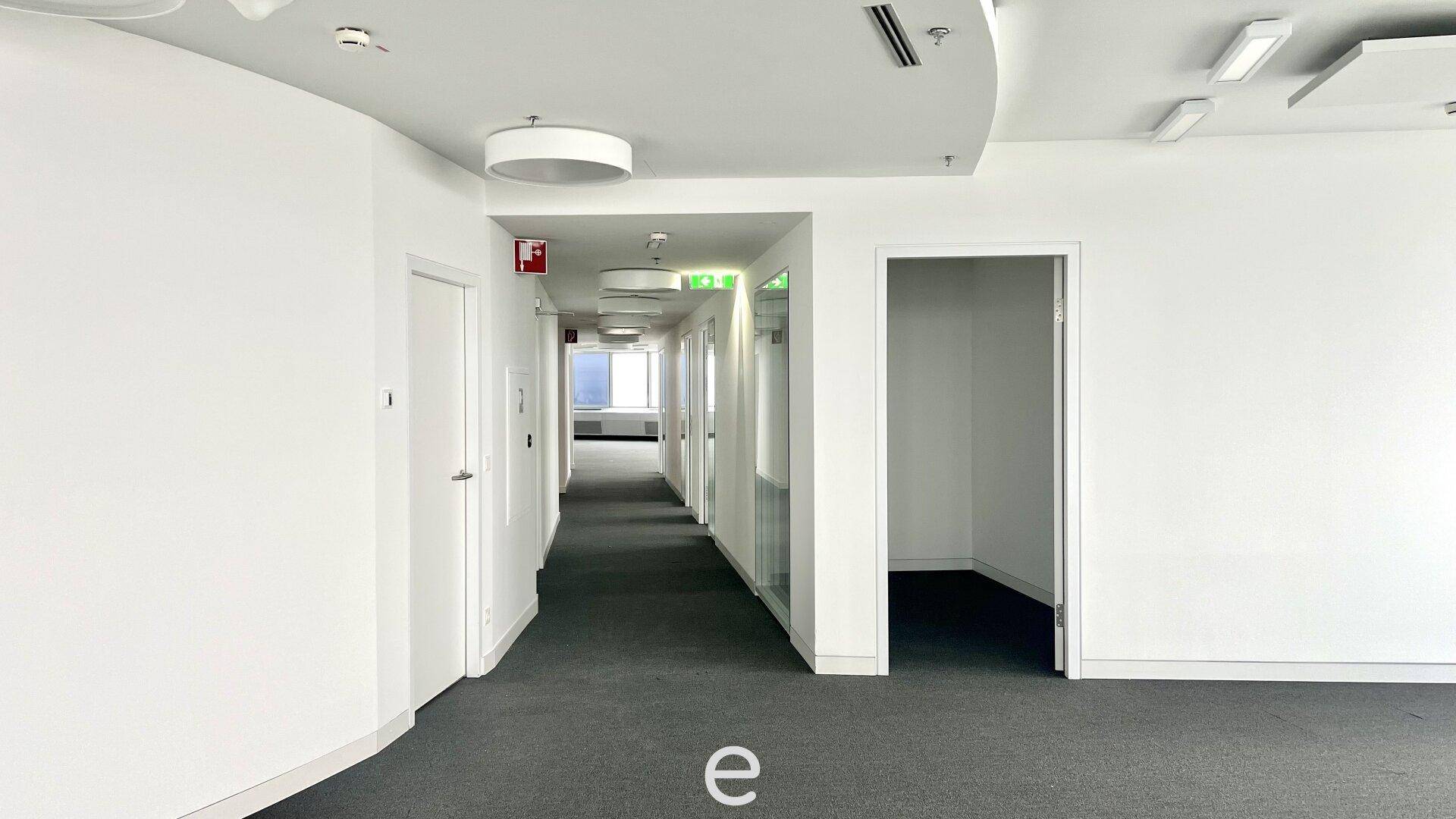 Langer Bürogang mit Teppichboden und mehreren Türen, der zu verschiedenen Büroräumen führt.