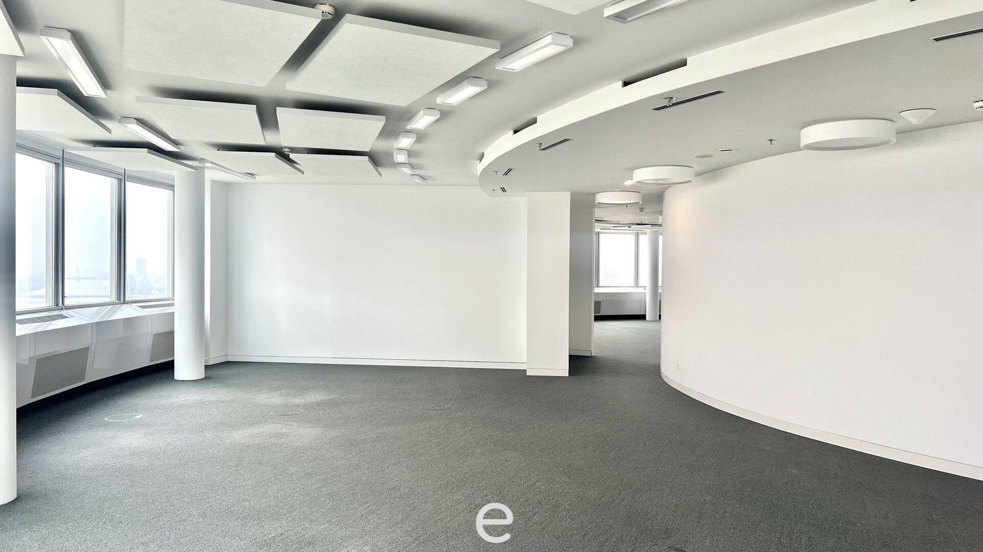 Leerer, unmöblierter Büroraum mit Teppichboden, großen Fenstern und geschwungenen Wänden, bereit zur individuellen Gestaltung.