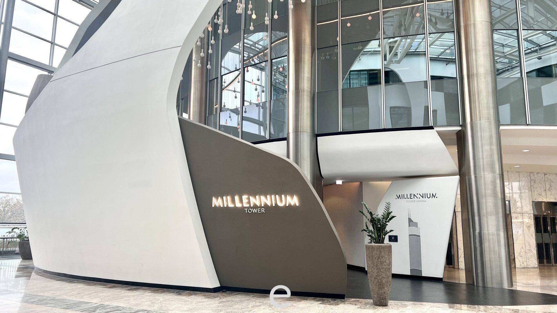 Moderner Eingangsbereich des Millennium Towers mit geschwungenen Wänden, hohen Decken und stilvoller Beschilderung.