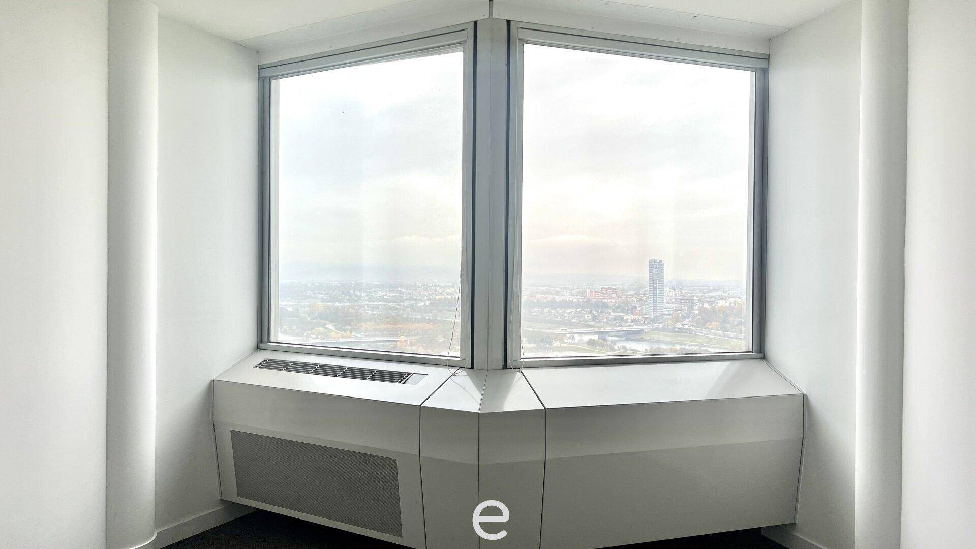 Eckbüro mit zwei großen Fenstern, die einen weiten Blick auf die Stadtlandschaft ermöglichen.