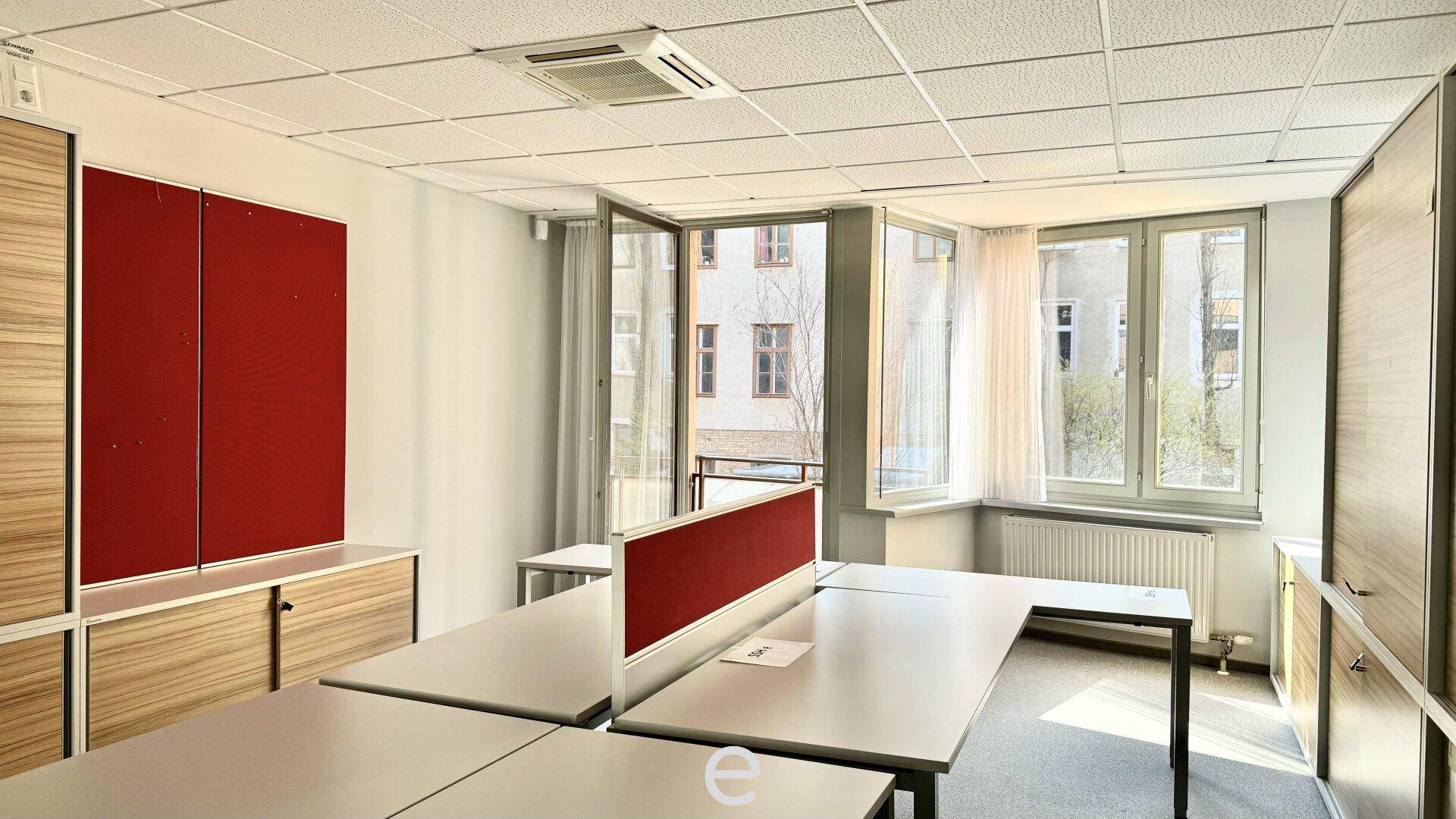Heller Büroraum mit Arbeitsplätzen, Stauraum und großen Fenstern mit Blick auf die Umgebung.
