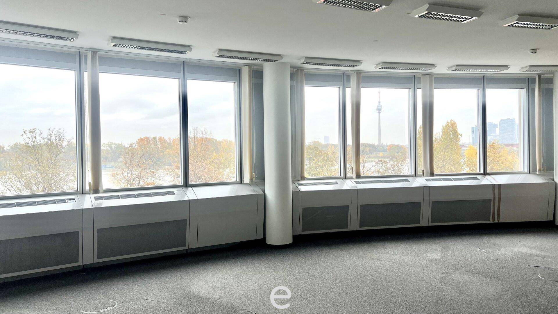 Geräumiges Büro mit Teppichboden und einer Reihe großer Fenster, die einen weiten Blick bieten.