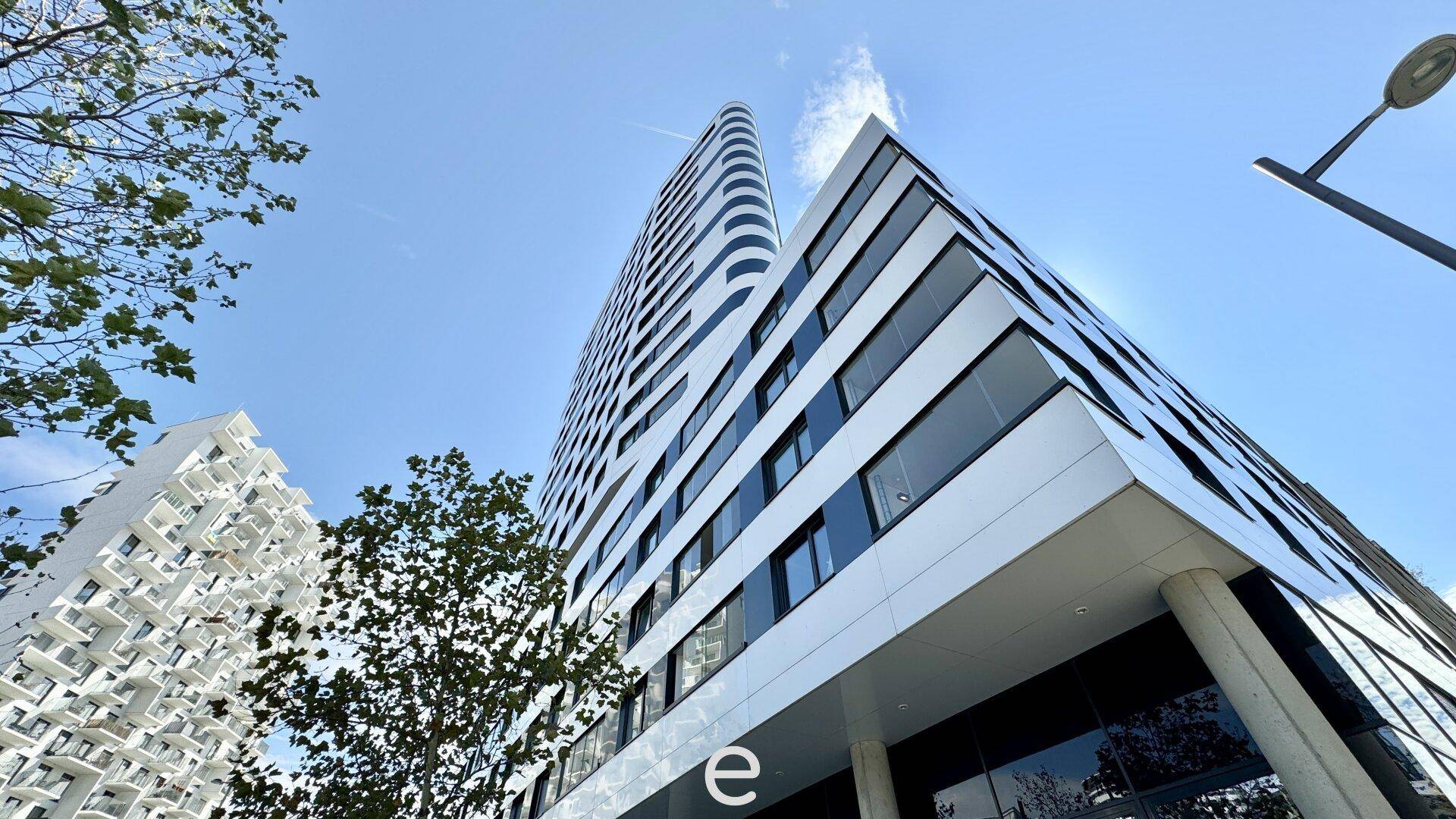 Moderne Hochhausarchitektur mit markanter Fassade und vielen Fenstern unter blauem Himmel.