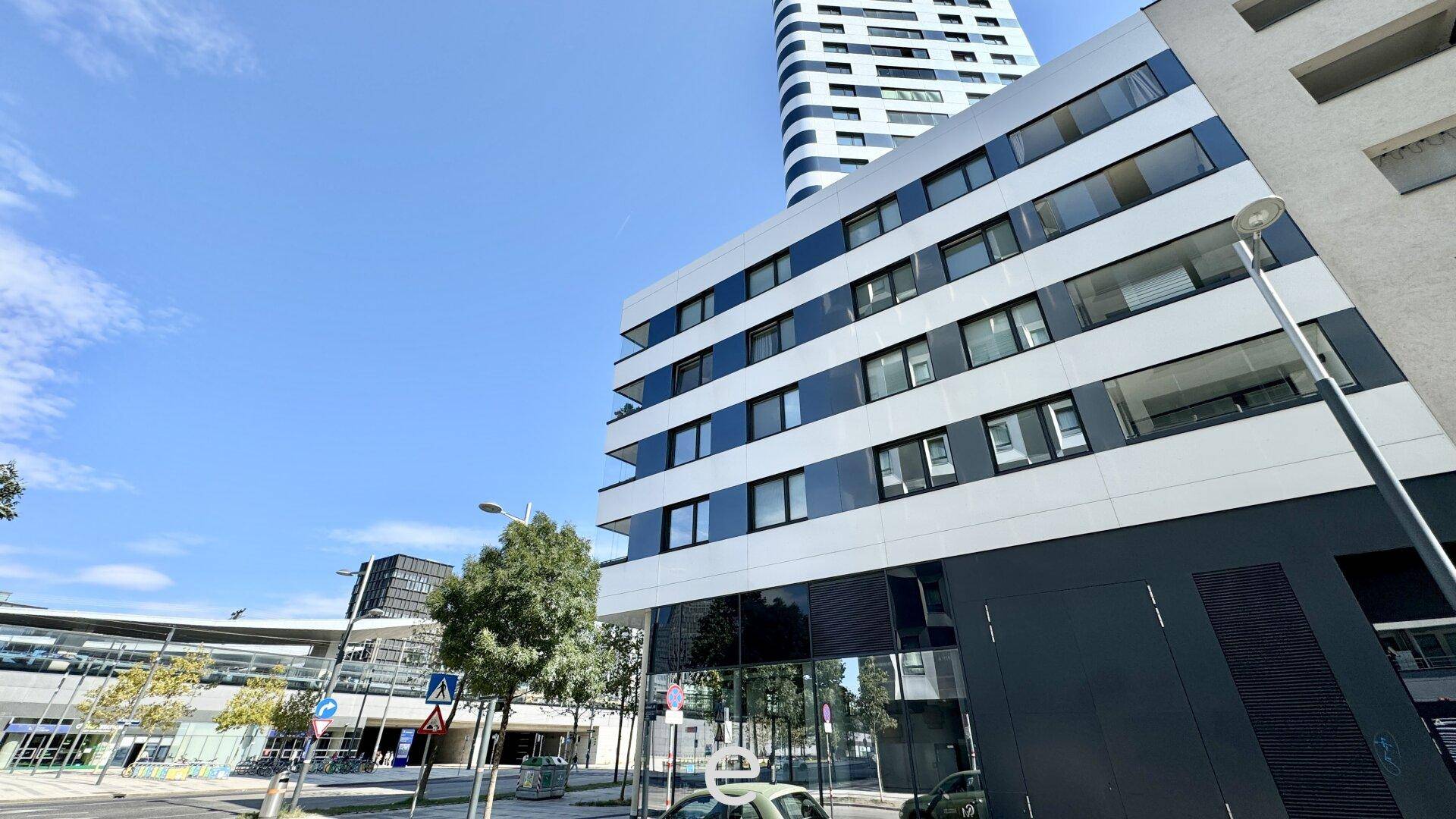 Moderne Gebäudefassade mit großen Fenstern und Balkonen, Teil eines städtischen Komplexes.
