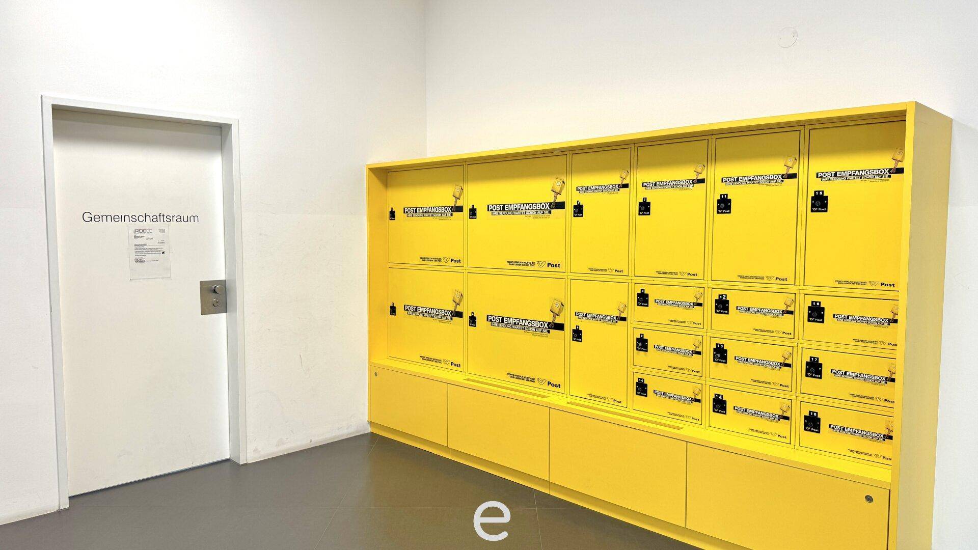 Gemeinschaftsraum mit gelben Paketfächern und einer Tür zum Gemeinschaftsraum.