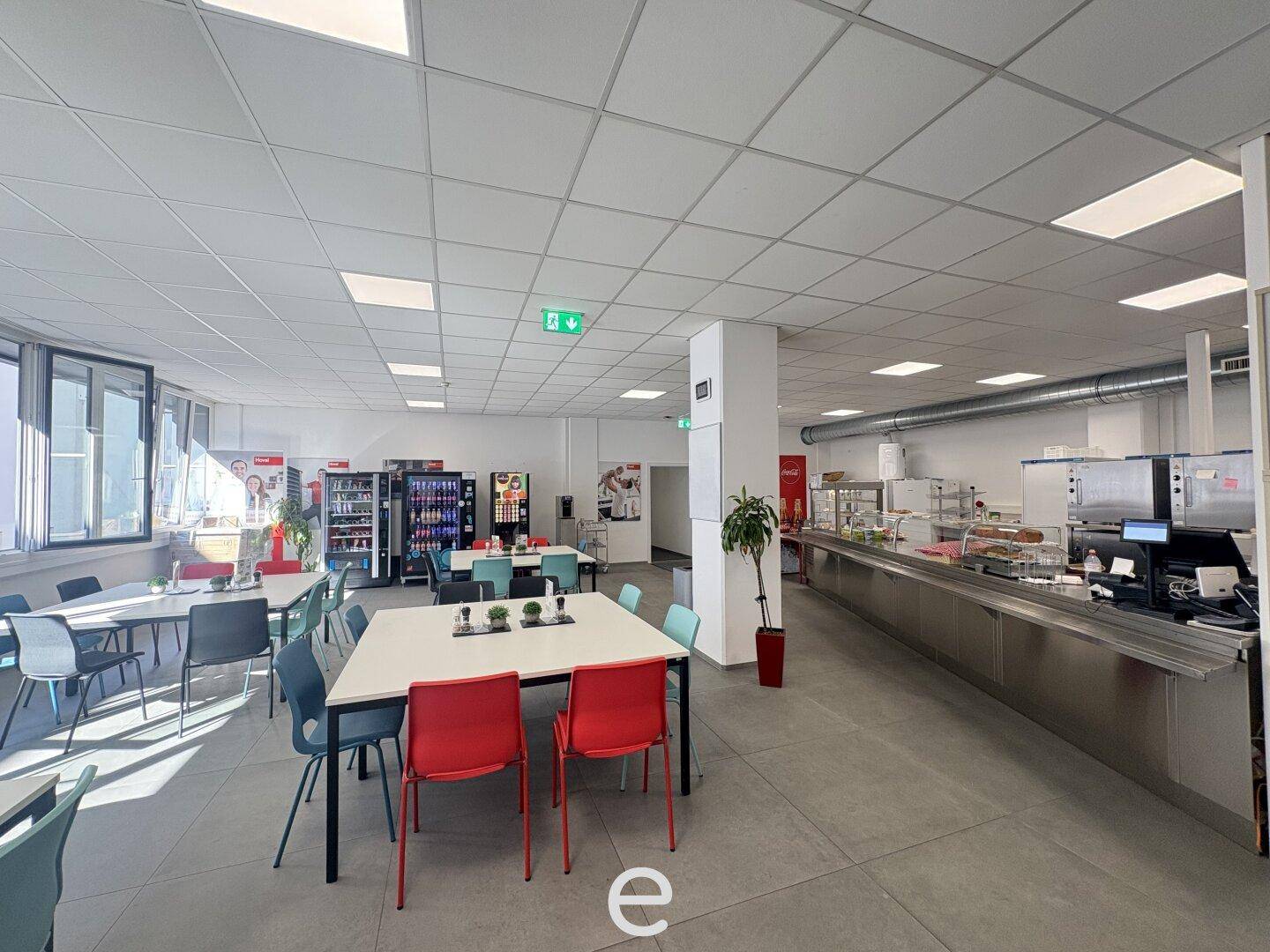 Geräumige Kantine mit Essbereich, Selbstbedienungstheke und mehreren Verkaufsautomaten.