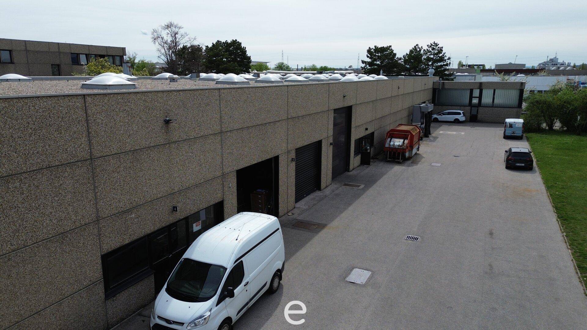 Außenansicht der Lagerhalle mit mehreren Rolltoren für LKW-Zufahrt und einem Lieferwagen.
