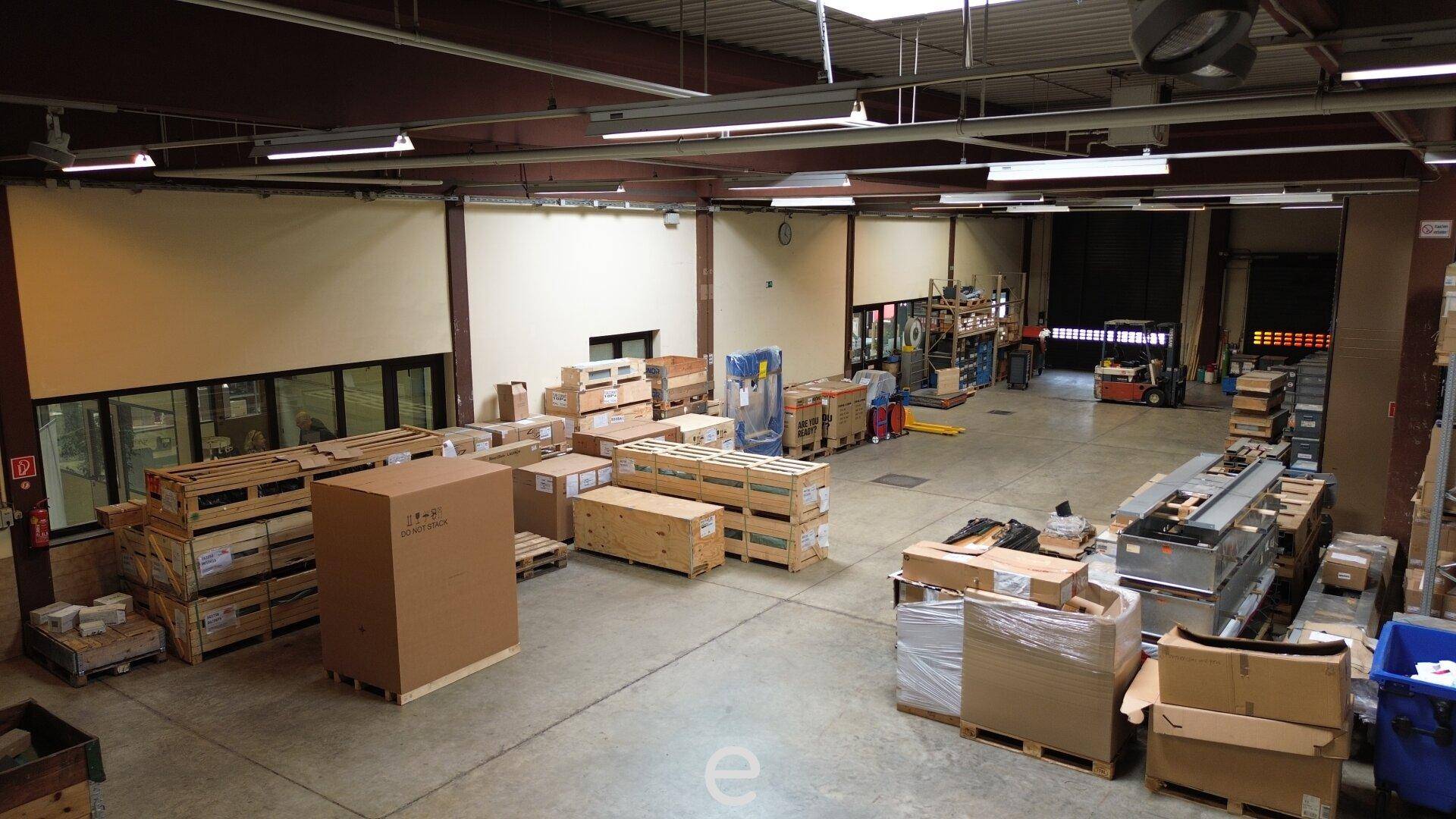 Große Lagerhalle mit vielen verpackten Waren, Paletten und Gabelstaplern bereit zur Verladung.