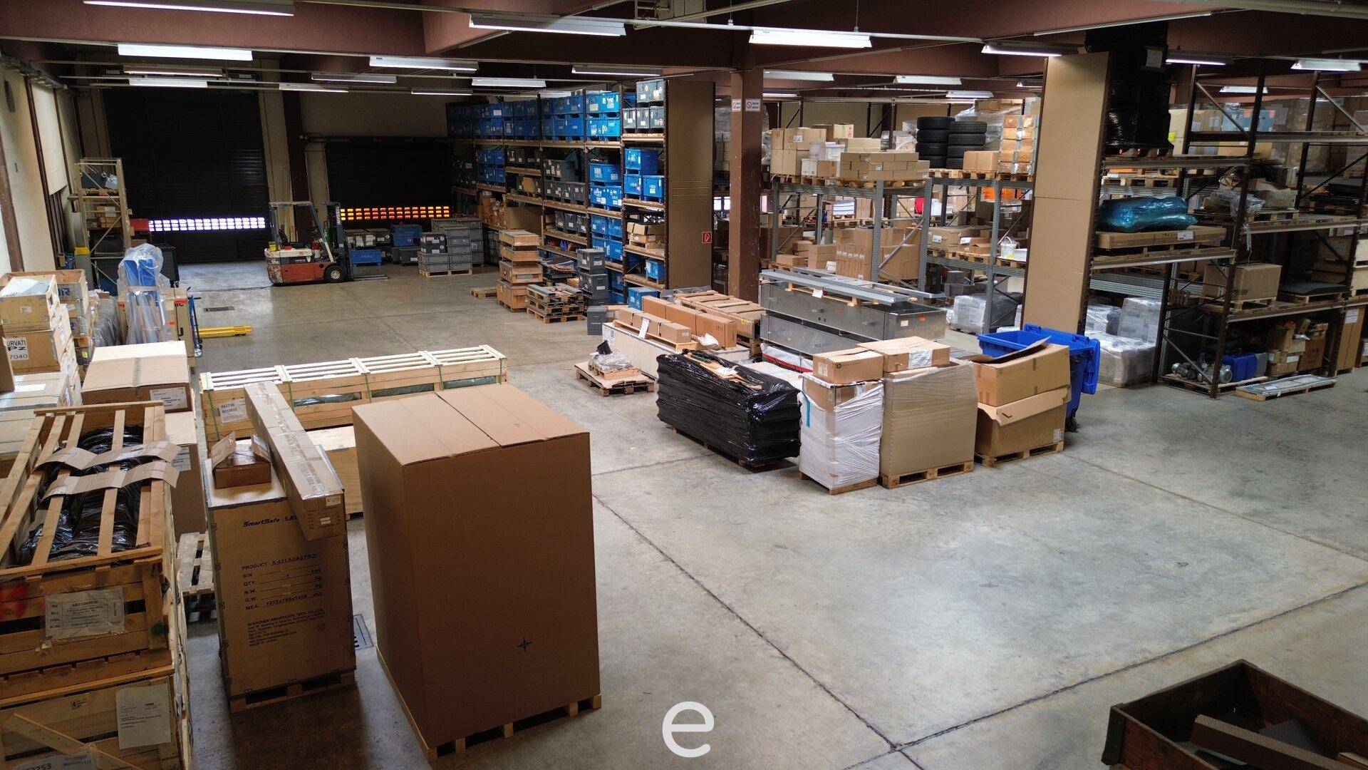 Geräumige Lagerhalle mit zahlreichen Paletten, Kartons und Regalsystemen für effiziente Logistik.