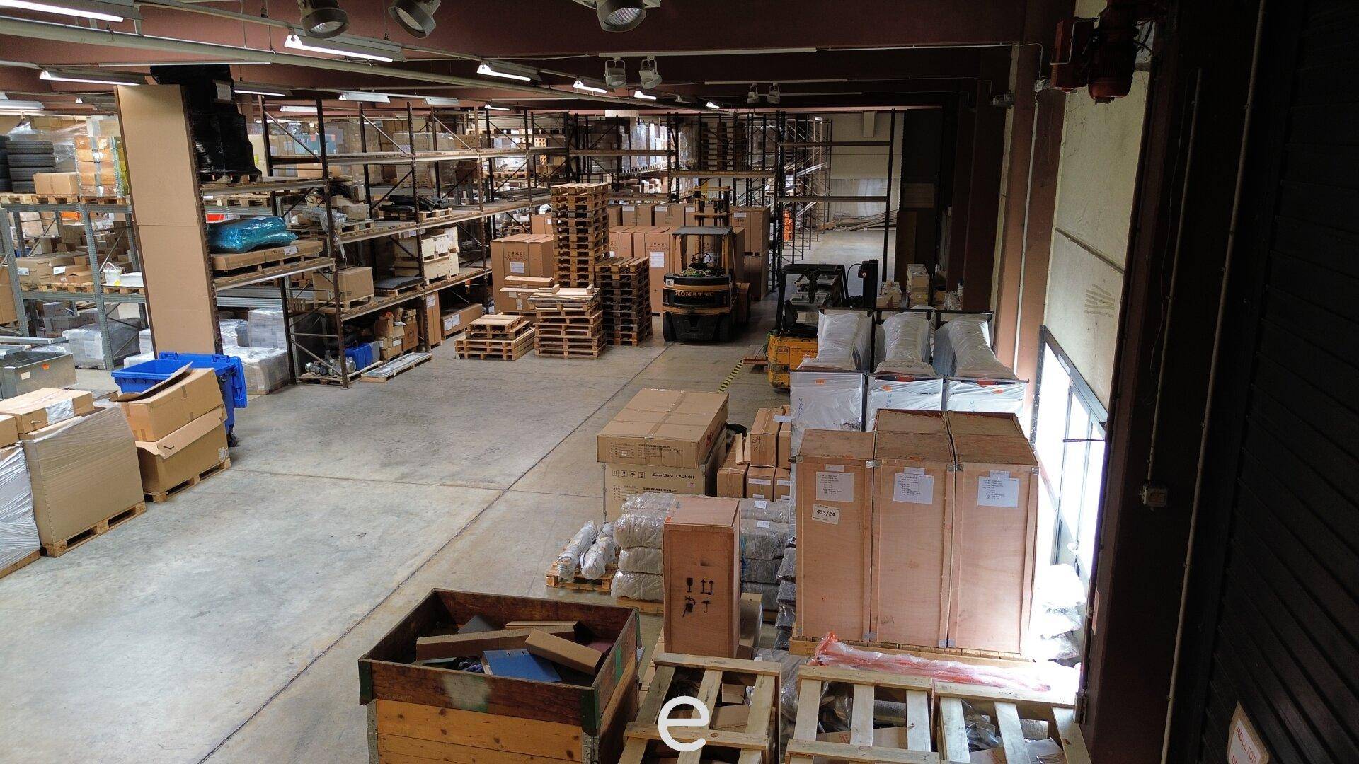 Innenansicht der Lagerhalle mit hohen Regalen, verpackten Gütern und viel Platz für Logistikabläufe.