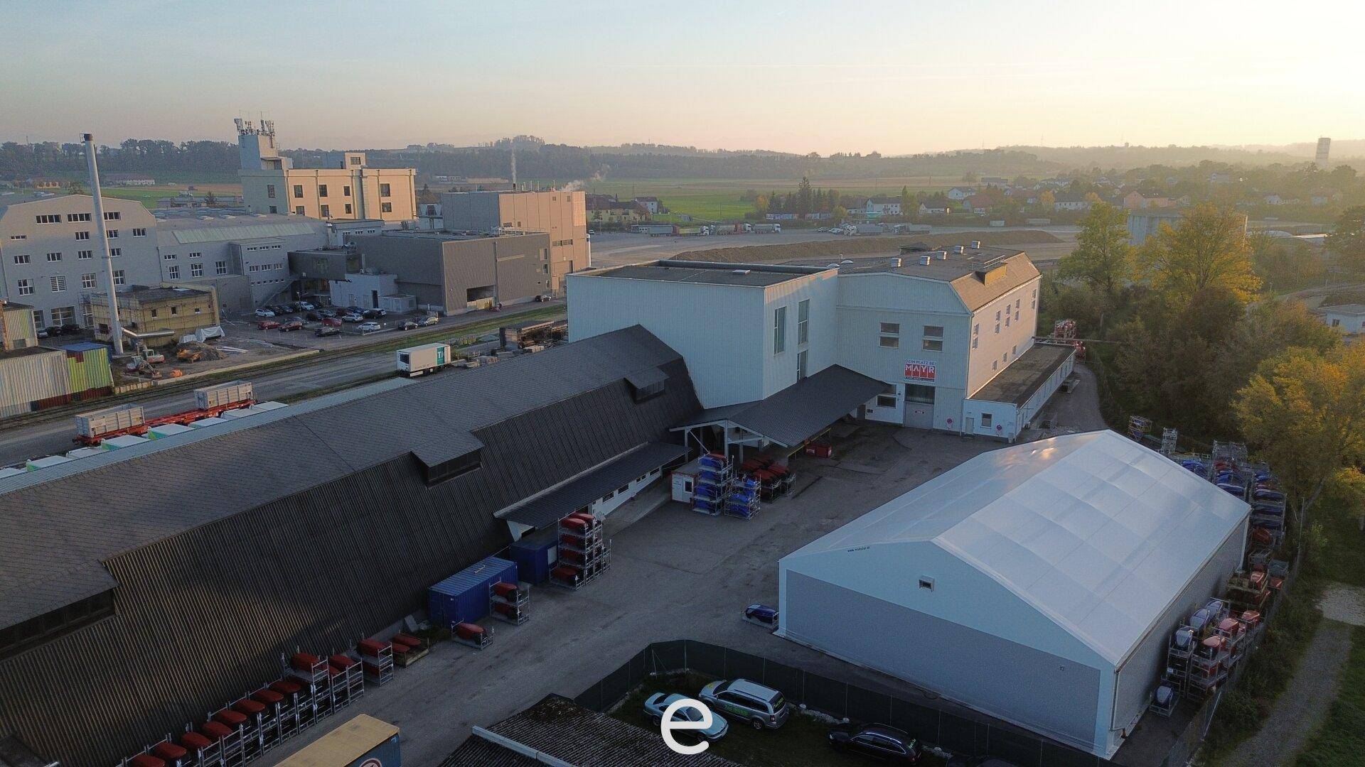 Überblick über ein weitläufiges Industrieareal mit verschiedenen Gebäuden und Lagerflächen unter klarem Himmel.