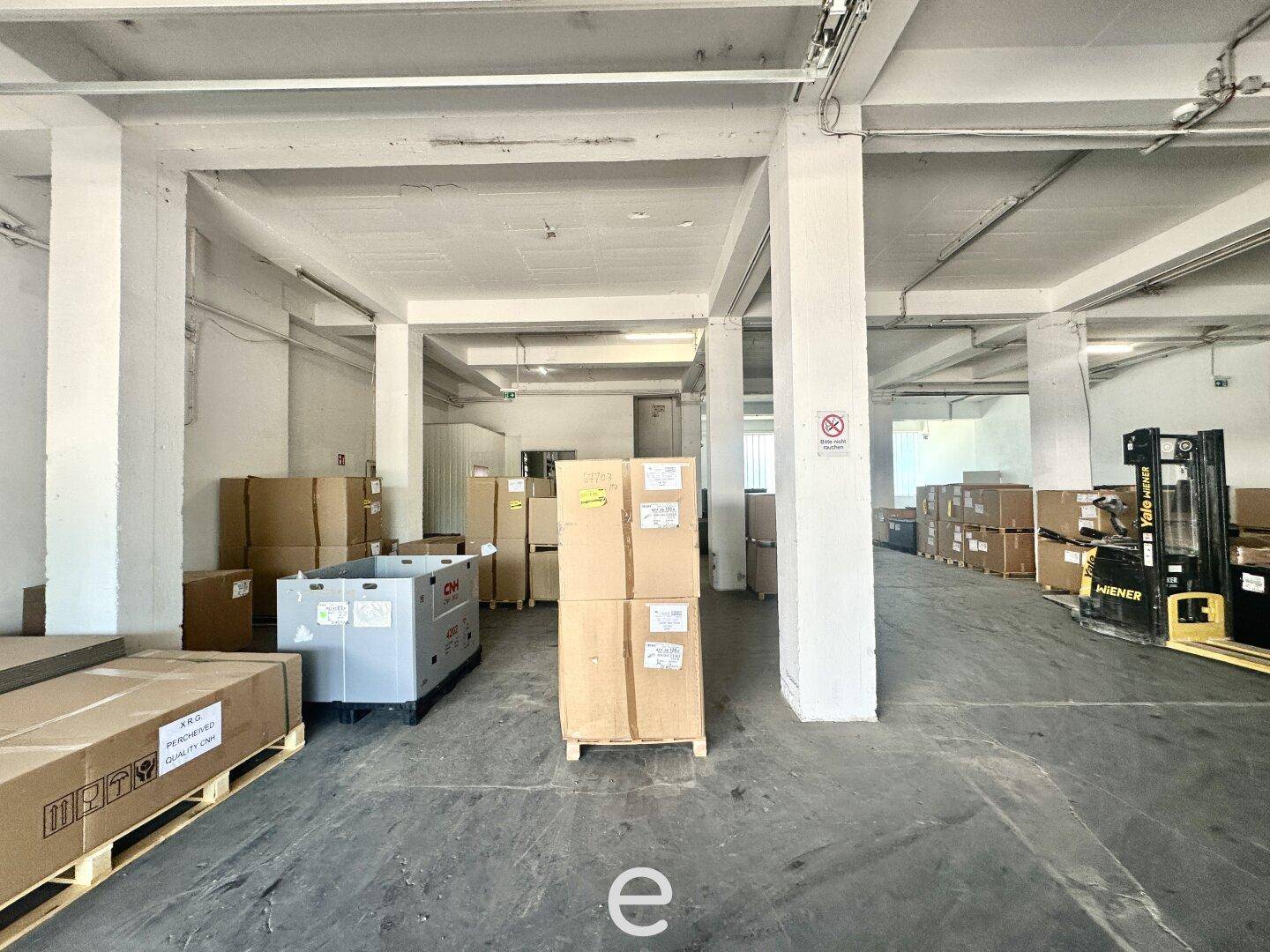 Lagerhalle mit gestapelten Waren, Paletten und Gabelstaplern, bereit für den Versand und Empfang.
