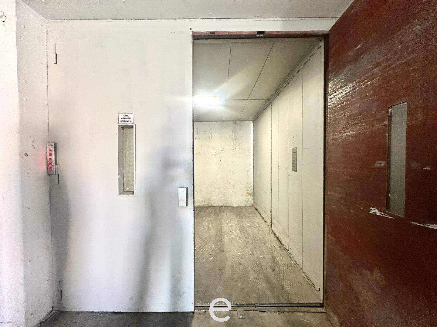Geöffneter Lastenaufzug in einem Industriegebäude, bereit zum Be- und Entladen von Waren.