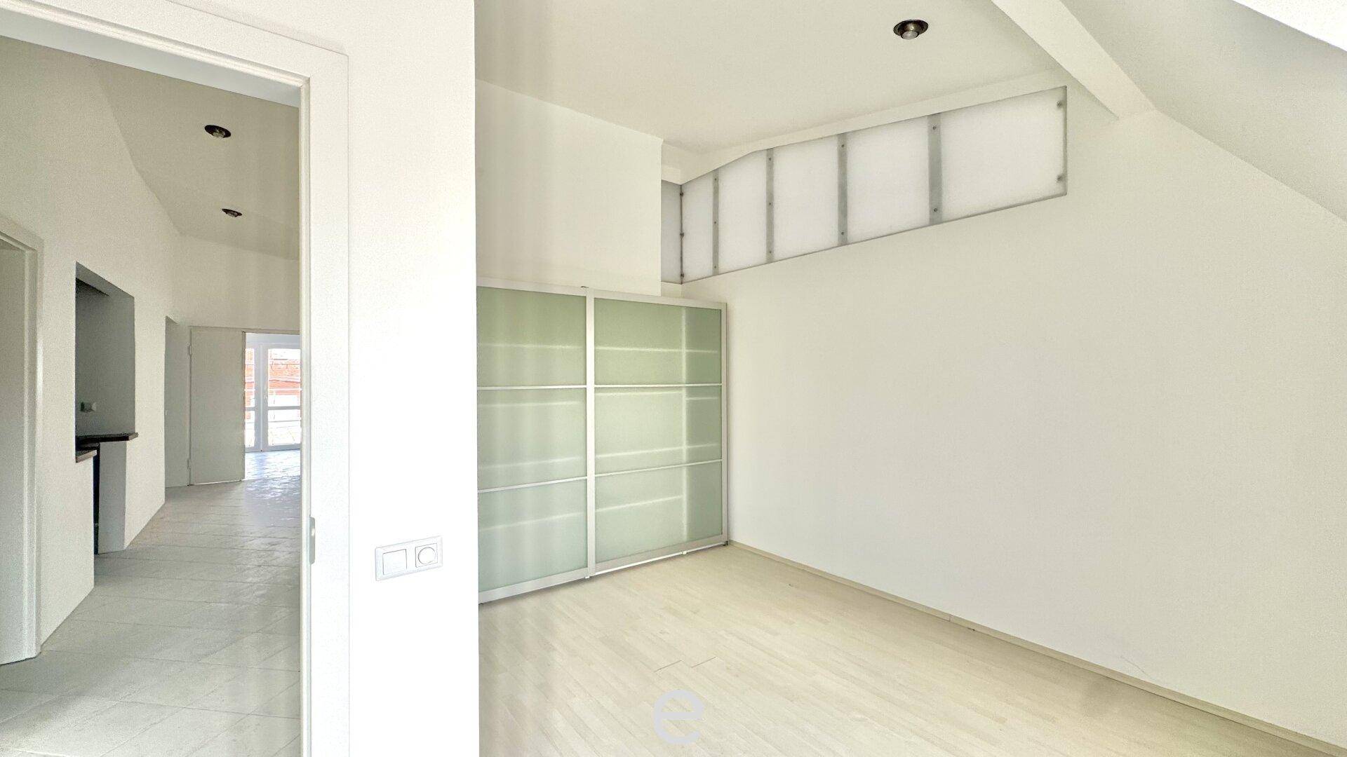 Schlafzimmer im Dachgeschoss mit Einbauschrank, schrägen Wänden und hellem Holzboden.