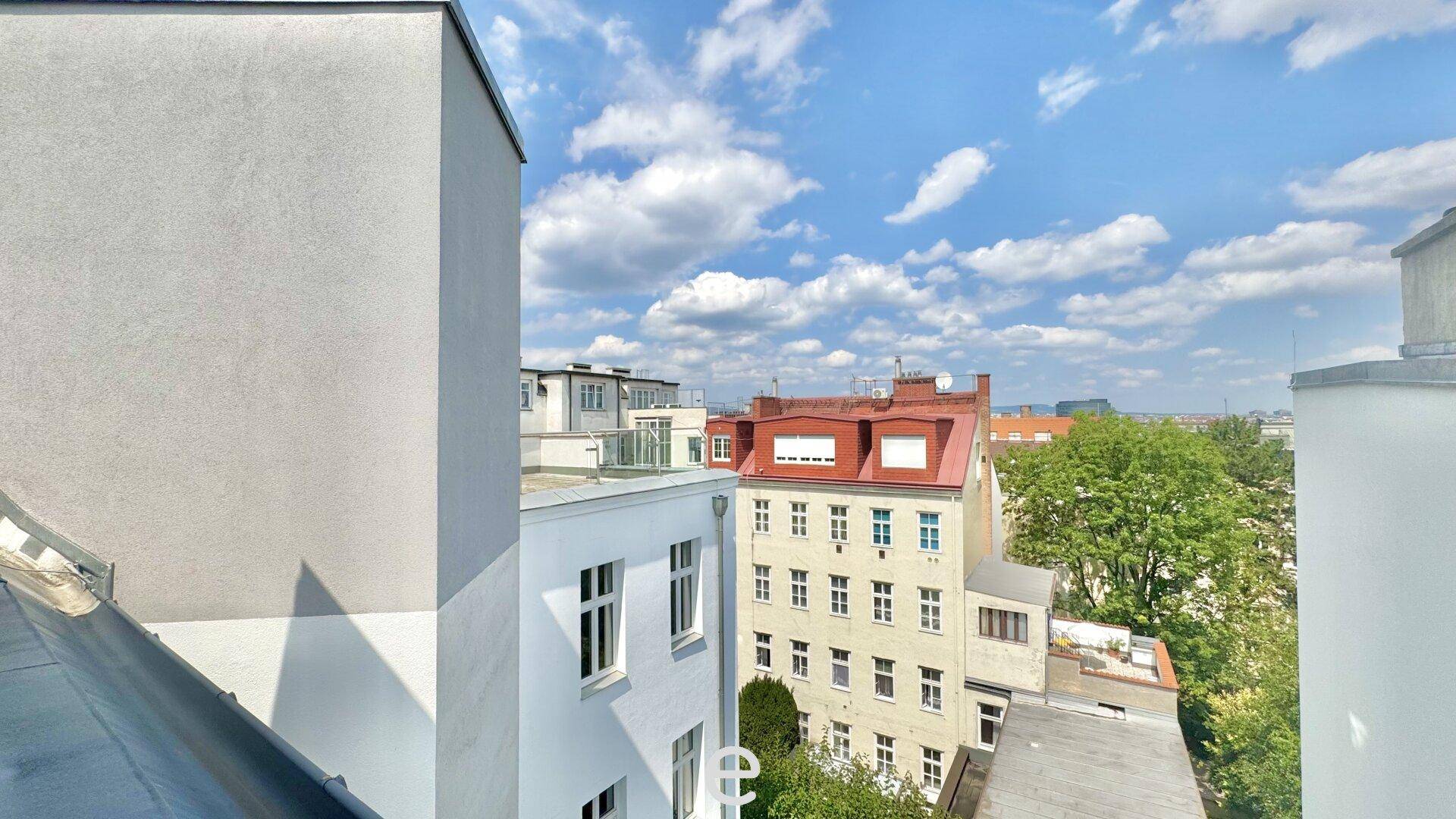Panoramablick über die Dächer der Stadt mit viel Grün und blauem Himmel.