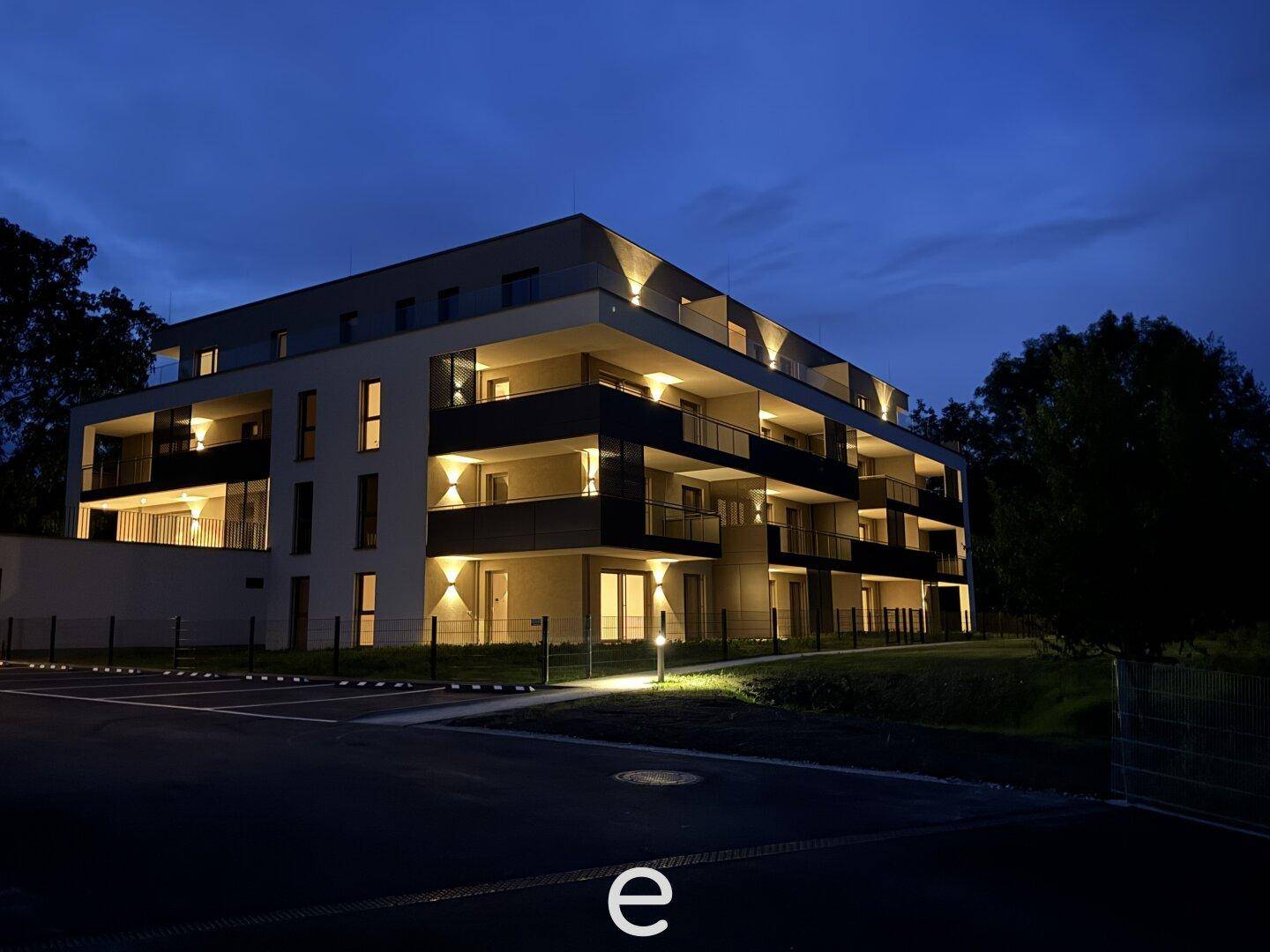 Moderne Wohnanlage bei Nacht mit beleuchteten Balkonen und Außenbereichen.
