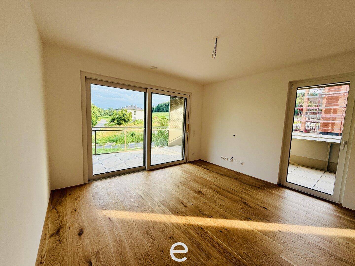 Heller Wohnraum mit Eichenparkett und Zugang zu einer Terrasse mit Weitblick.