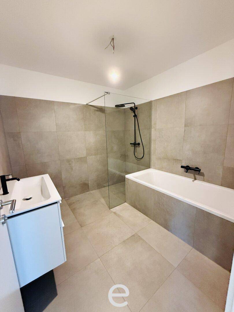 Modernes Badezimmer mit Badewanne, ebenerdiger Dusche und großformatigen Fliesen.