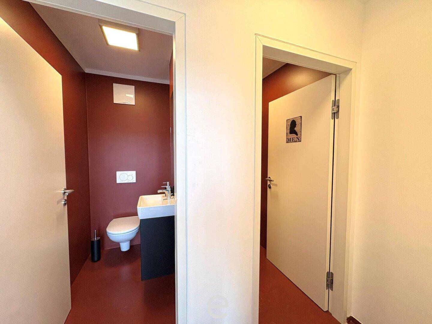 Zwei separate Toilettenräume mit modernen Armaturen und farbigen Wänden für Besucher.