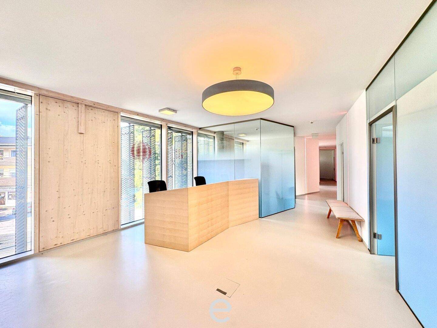 Heller Empfangsbereich mit moderner Theke, Glaswänden und großen Fenstern für viel Tageslicht.
