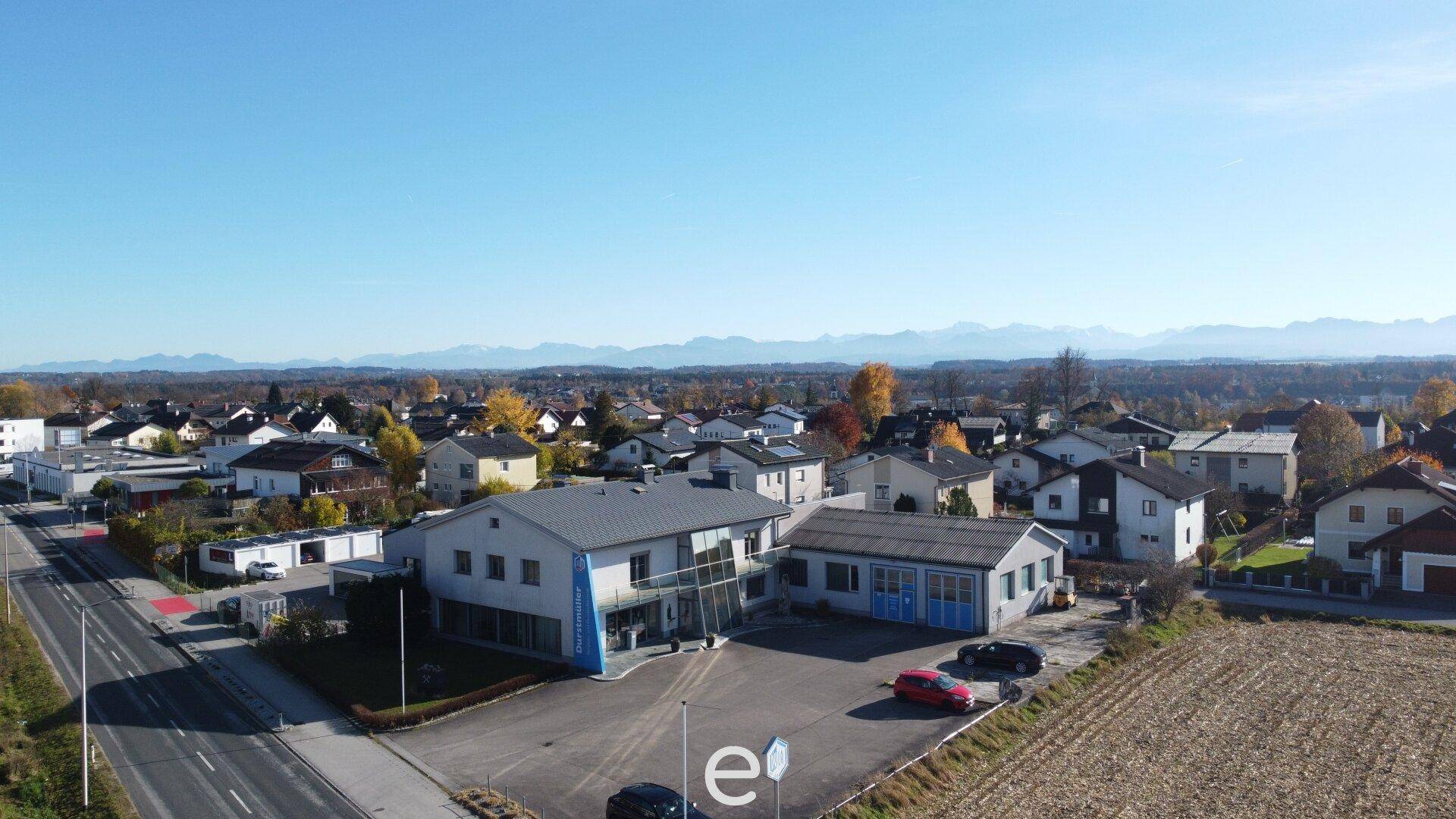 Luftaufnahme des Geschäftsgebäudes in einer ländlichen Umgebung mit Bergblick im Hintergrund.