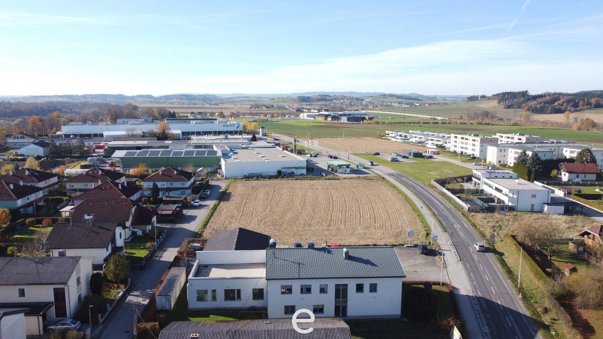 Weitläufige Luftaufnahme des Geschäftsgebäudes mit angrenzenden Feldern und Gewerbegebieten.