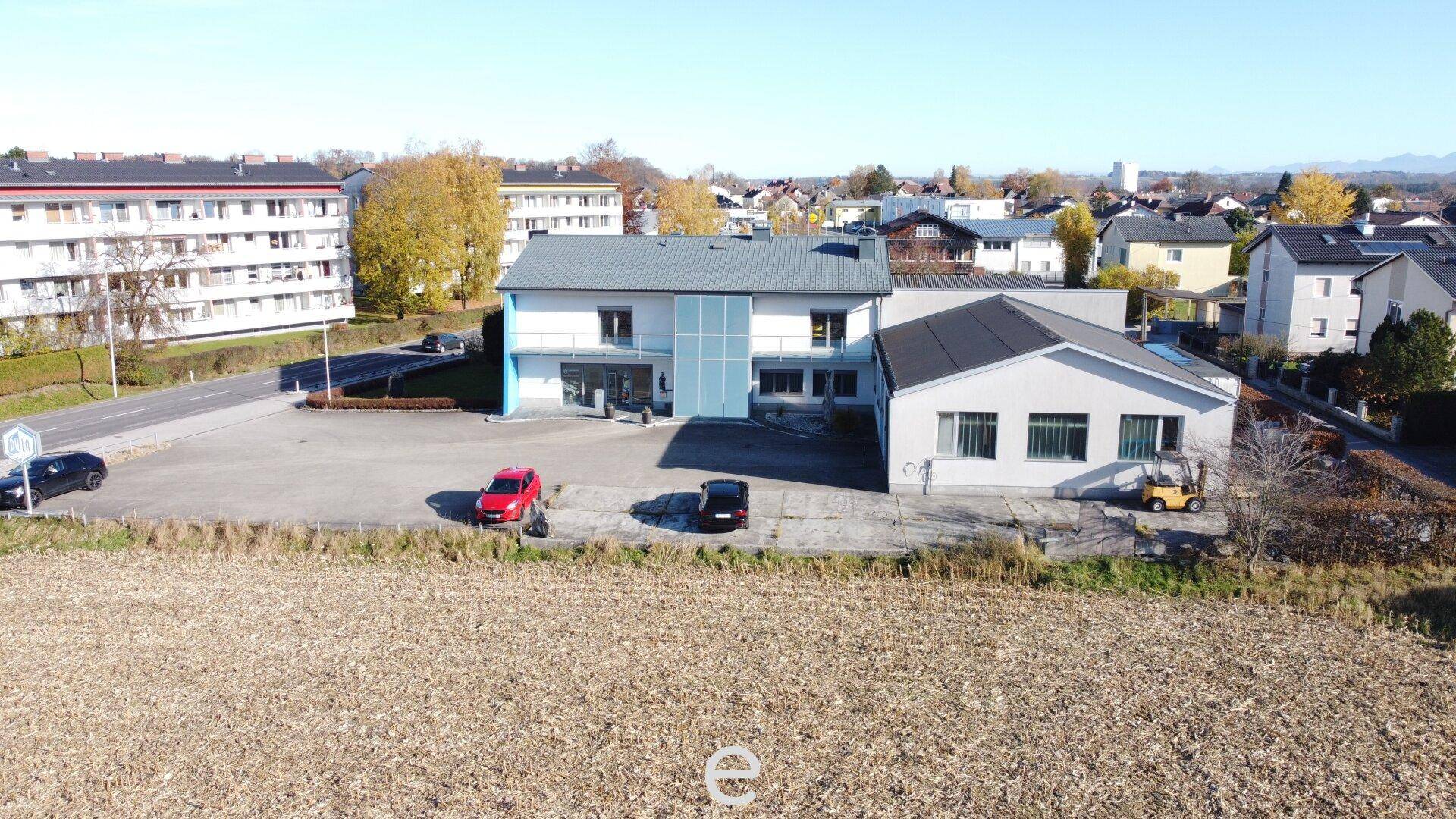 Luftaufnahme des Geschäftsgebäudes mit angrenzendem Feld und Wohngebäuden im Hintergrund.