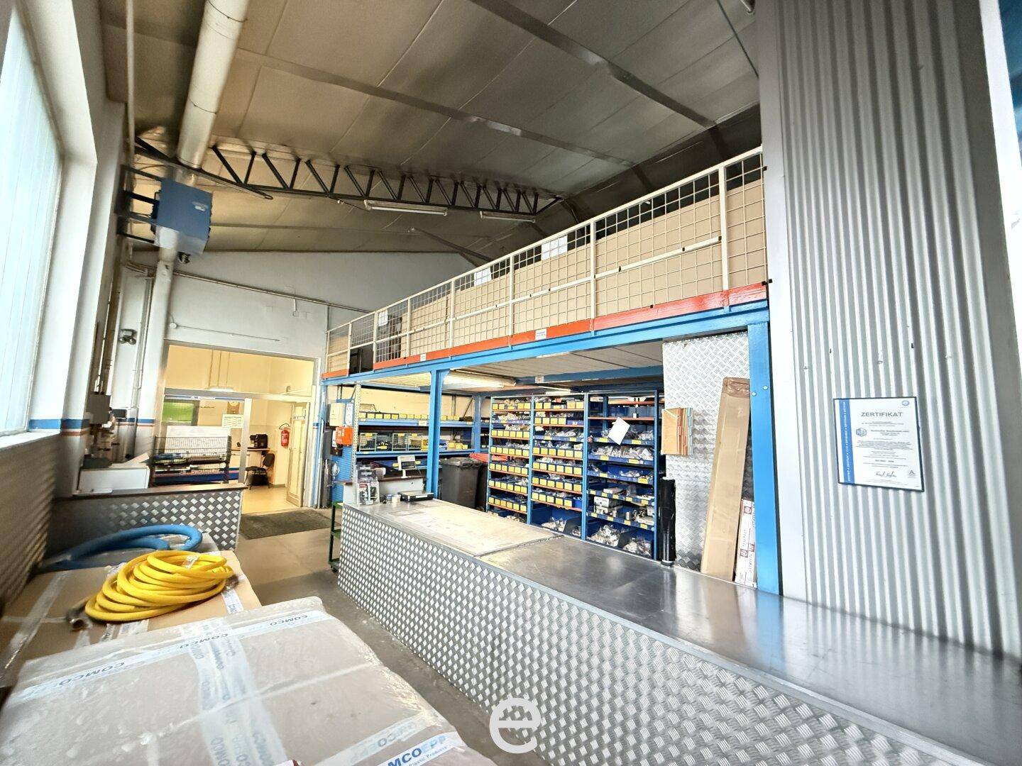 Industrielle Lagerhalle mit Metallregalen, Arbeitsbereich und hohen Decken.