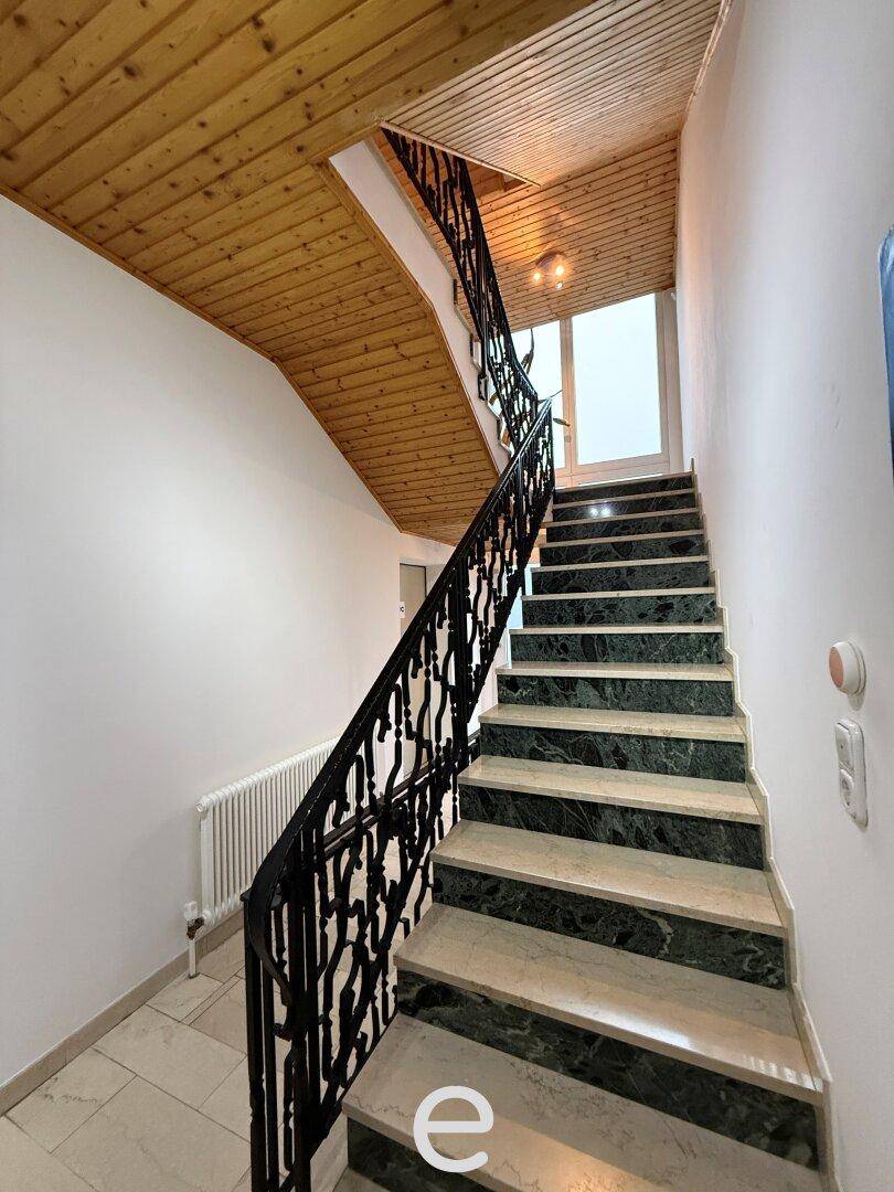 Treppenhaus mit Marmorstufen, schmiedeeisernem Geländer und Holzdecke.