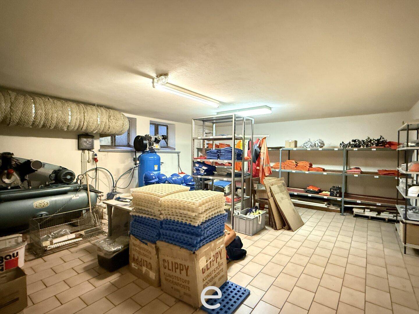 Kellerraum mit Fliesenboden, Regalen und verschiedenen Geräten für Lagerzwecke.