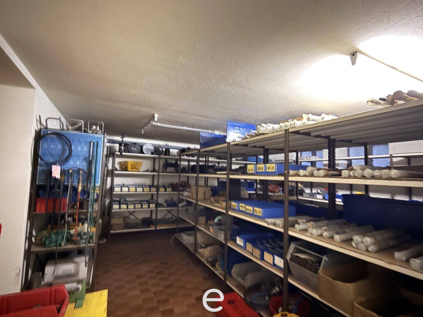 Lagerraum im Keller mit Regalen voller Artikel und Fliesenboden.