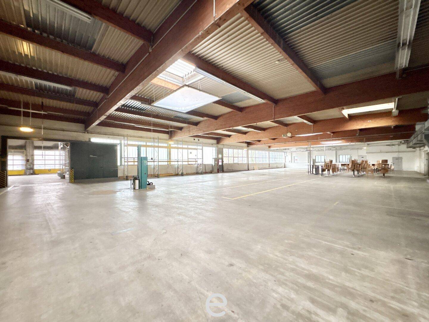 Weitläufige Lagerhalle mit Betonboden, hohen Decken und Oberlichtern, bietet vielseitige Nutzungsmöglichkeiten.