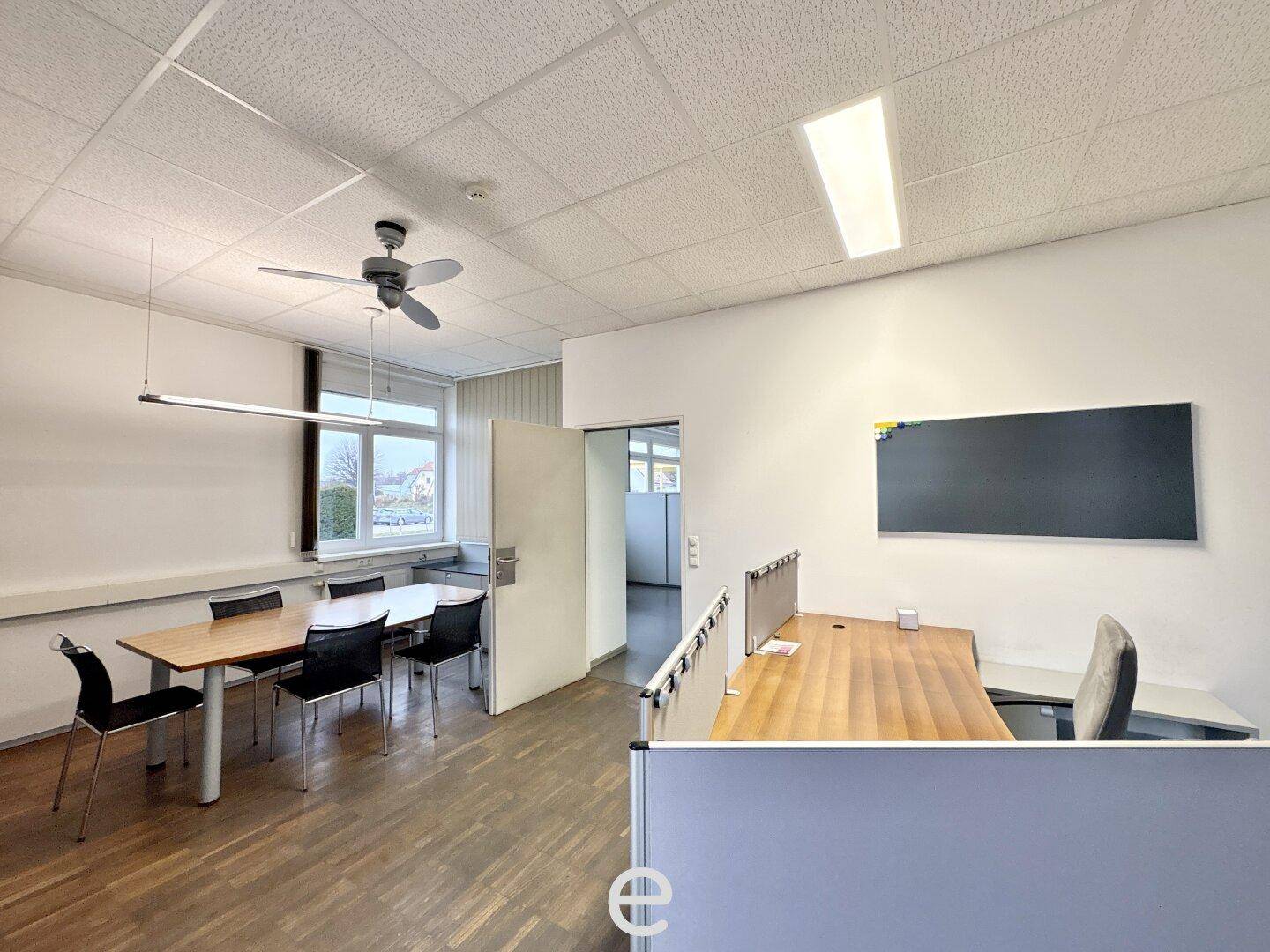 Geräumiges Büro mit Holzboden, Deckenventilator und flexiblem Arbeitsbereich, bietet Platz für mehrere Mitarbeiter.
