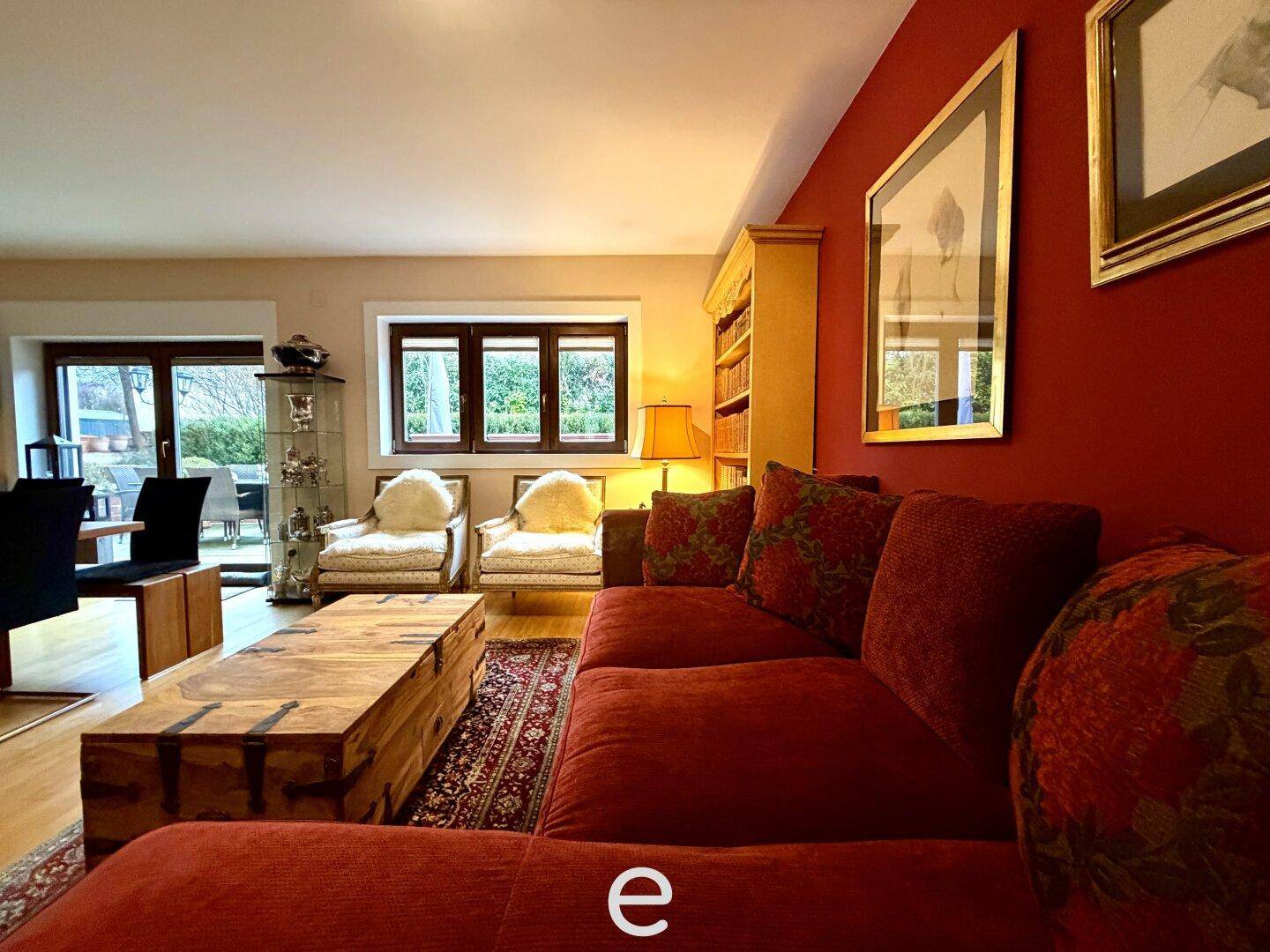 Wohnzimmer mit großem roten Sofa, Teppich und Blick in den Essbereich.