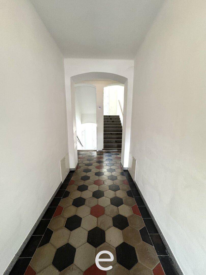 Historischer Eingangsbereich mit gemusterten Fliesen und Treppenaufgang.