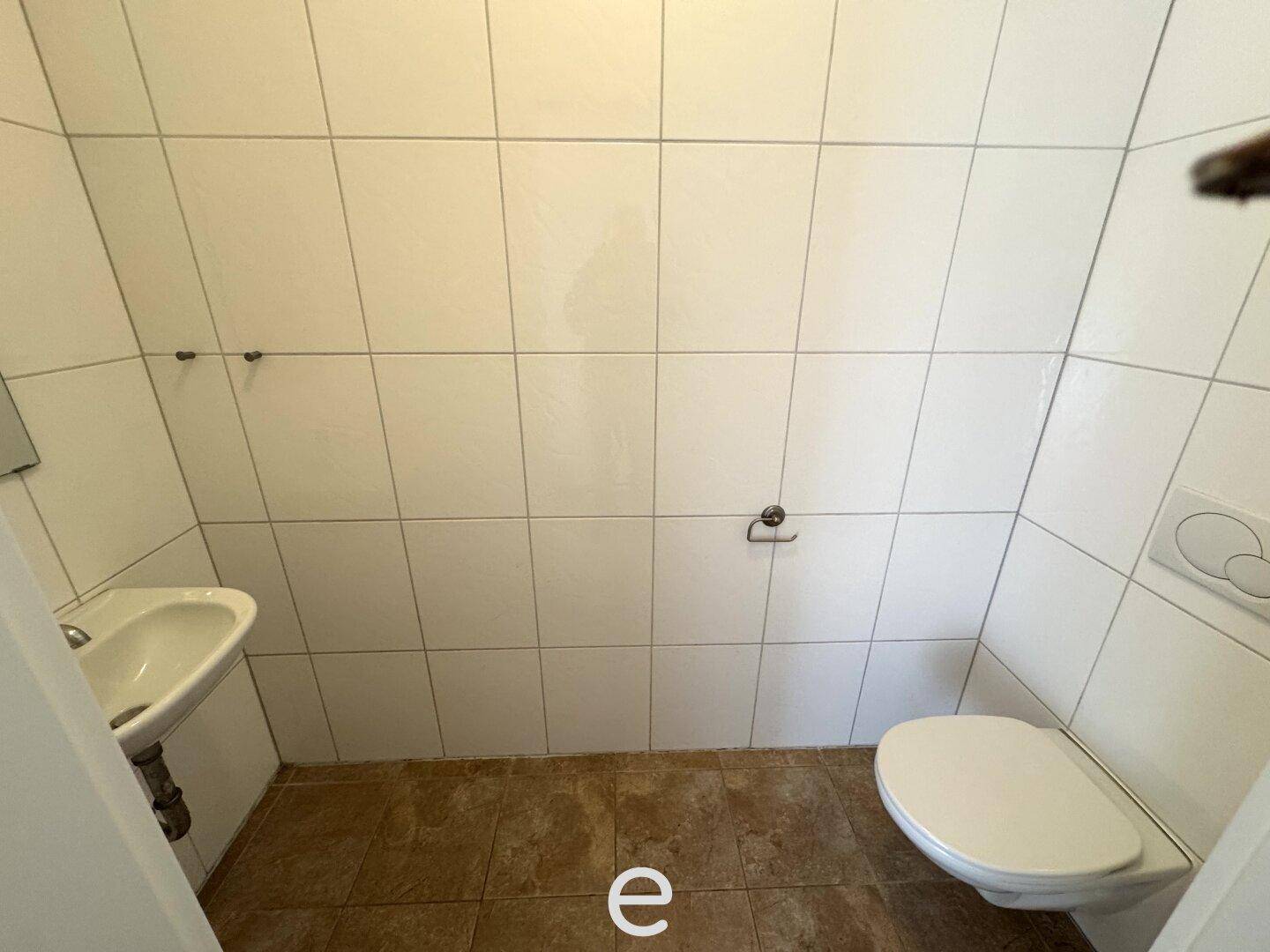 Kleines Gäste-WC mit WC, Waschbecken und weißen Wandfliesen.