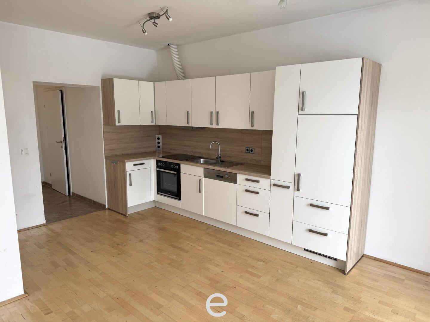 Moderne Einbauküche mit weißen Schränken, Holzoptik-Arbeitsplatte und integrierten Geräten.