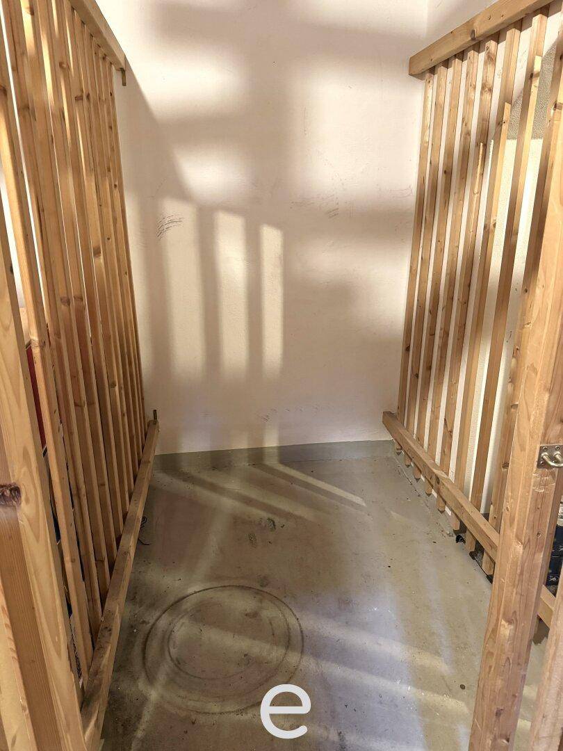 Kellerabteil mit Holzlattenwänden und Betonboden für sichere Lagerung.