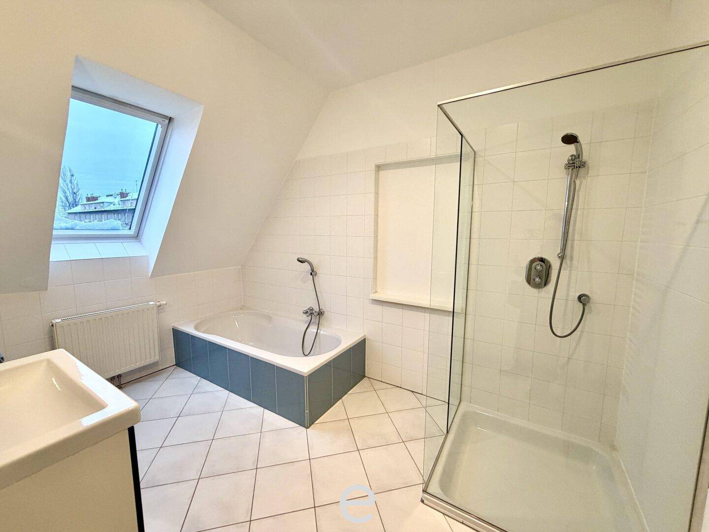 Helles Badezimmer im Dachgeschoss mit Badewanne, separater Dusche und Dachfenster.