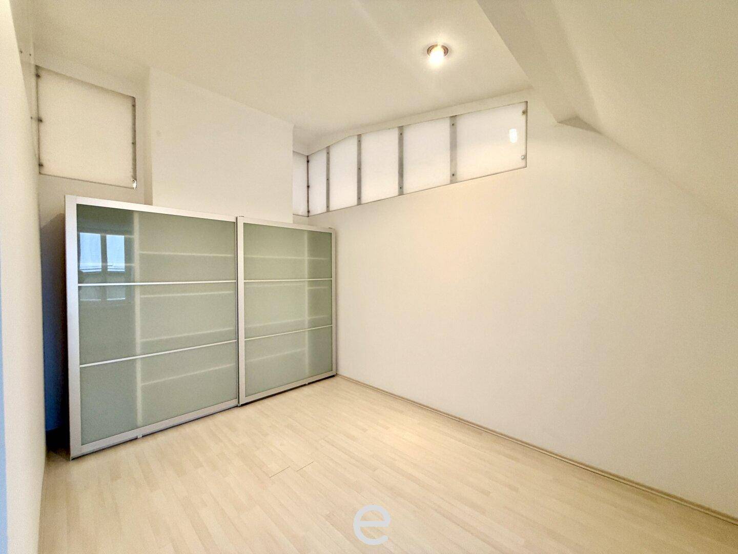 Schlafzimmer mit hellem Holzboden und einem praktischen Einbauschrank mit Schiebetüren.