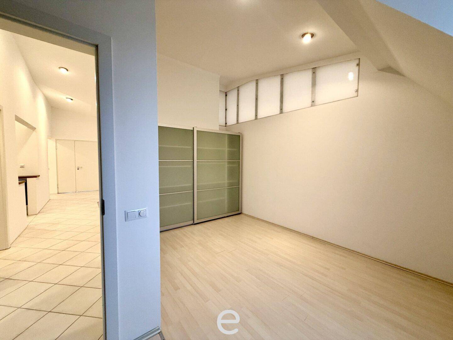 Helles Schlafzimmer mit Holzboden, integriertem Schrank und Zugang zu weiteren Räumen.