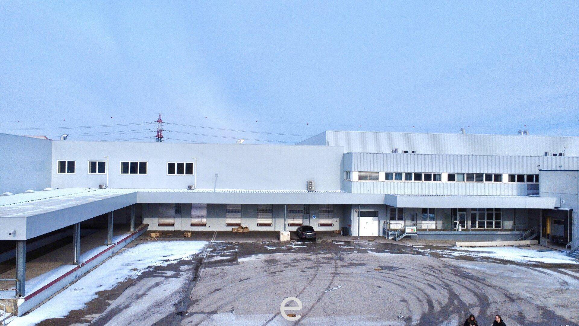 Weitläufige Außenansicht eines Industriegebäudes mit mehreren Laderampen und verschneitem Vorplatz.