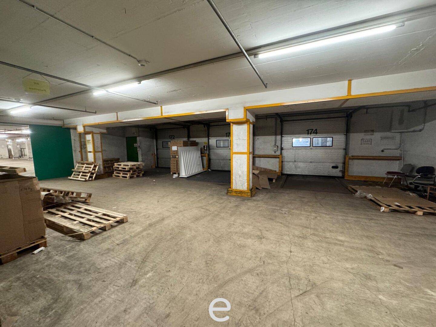 Großer Lagerraum mit Betonboden, Säulen und mehreren Rolltoren für den Warenumschlag.