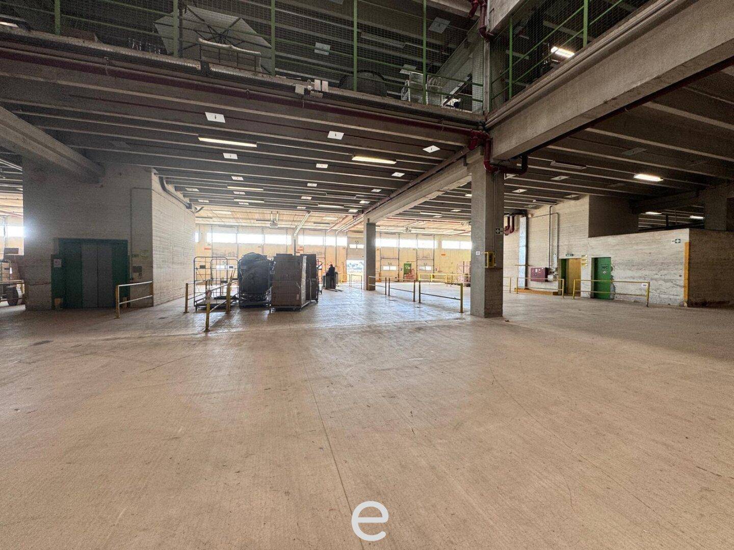 Großer, offener Bereich in einer Lagerhalle mit Betonboden und hohen Decken.