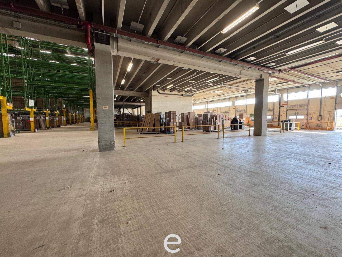 Großer, leerer Lagerbereich mit Betonboden und hohen Decken, ideal für Logistik.