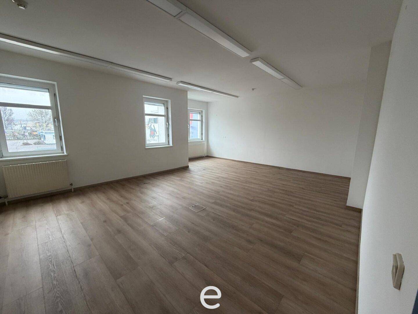 Großes, helles Büro mit Laminatboden und vielen Fenstern, bietet viel Tageslicht und Raum.